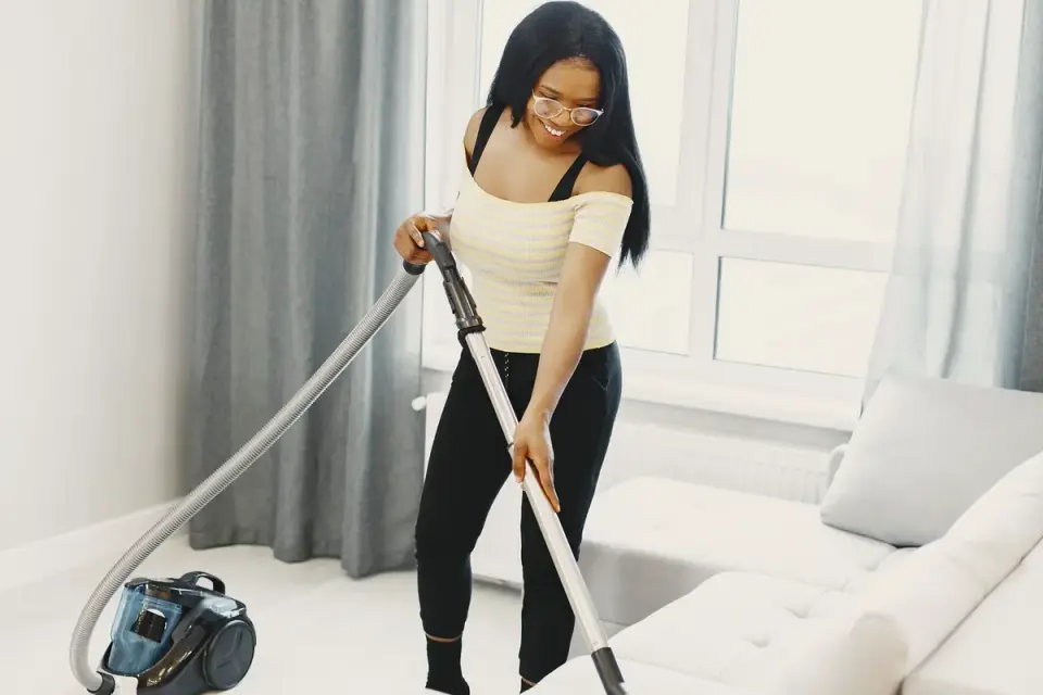 A woman vacuuming dog hair from a couch cushion
