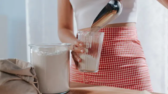 An owner holding a joint supplement chew next to a measuring scoop of powder on a kitchen counter